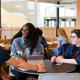 Students laughing sitting around a table in student centre