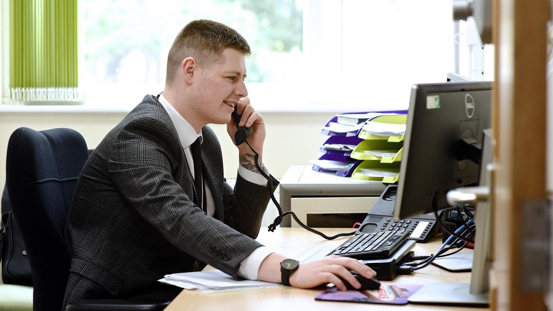 An apprentice answers the phone at a business.