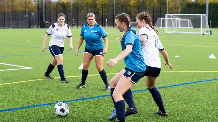 Students develop their player skills during a game of football.