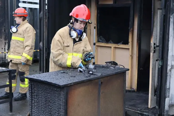 A student investigating an item at a fire investigation scene