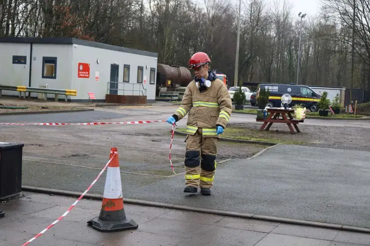 A student setting up a barrier at a fire investigation scene