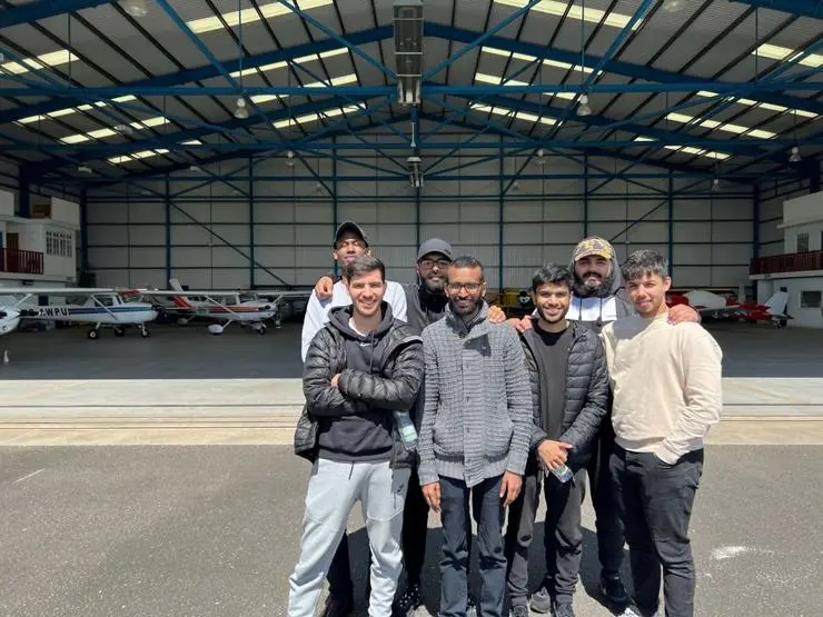 Students stood next to their tutor in front of an aircraft hanger