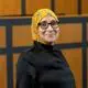 Dr Awasha Atiega in a black silk top  and black glasses and yellow hijab smiling