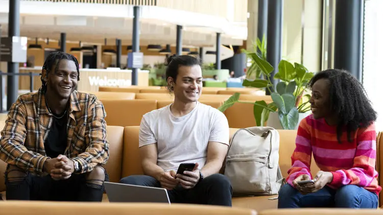 three students in the student centre sat on a sofa