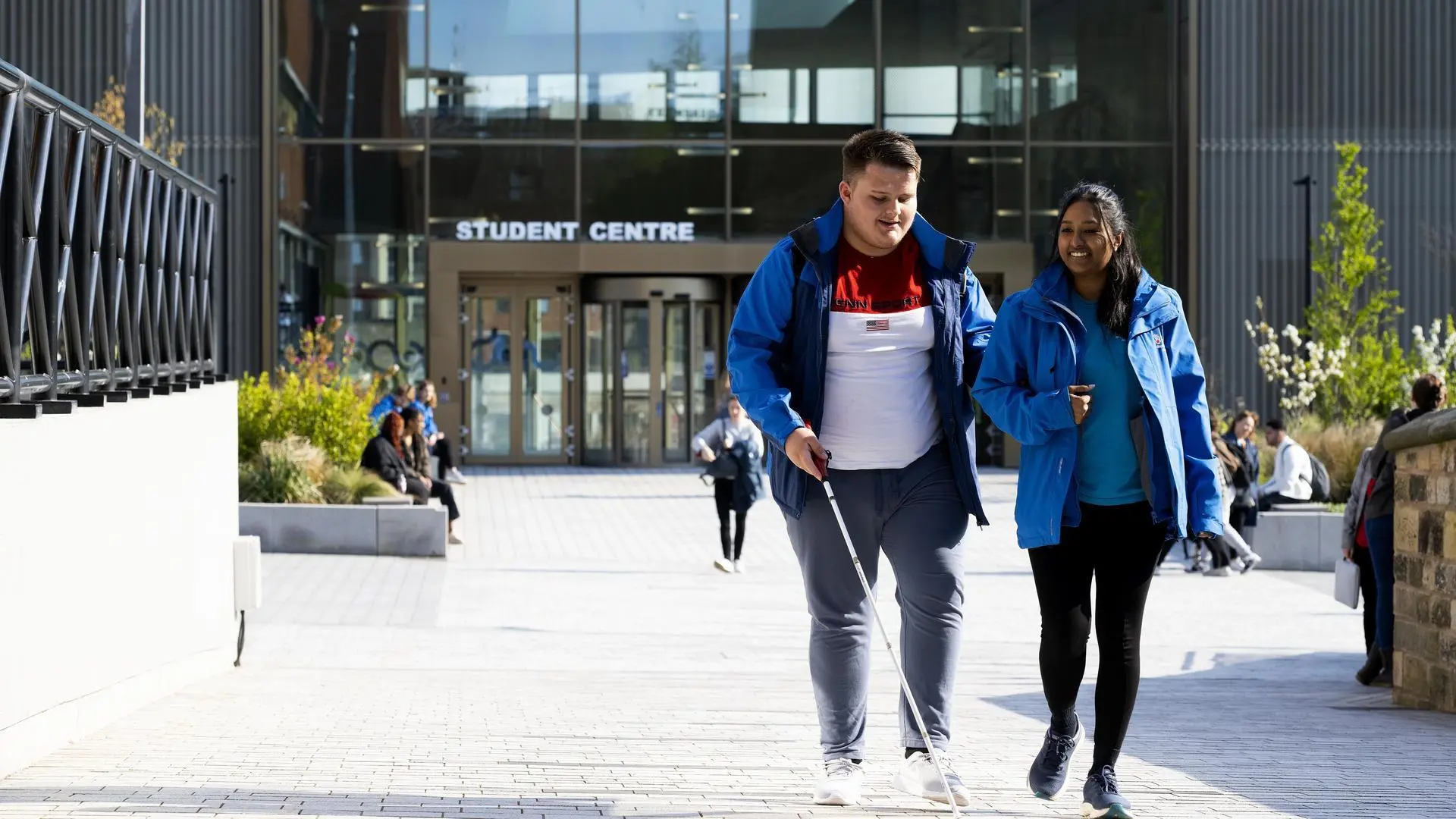 Blind student Llyod Sakr is being guided by a wellbeing ambassador.