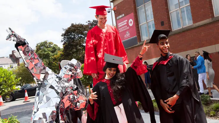 Graduates dancing with mirror man outside graduation ceremony