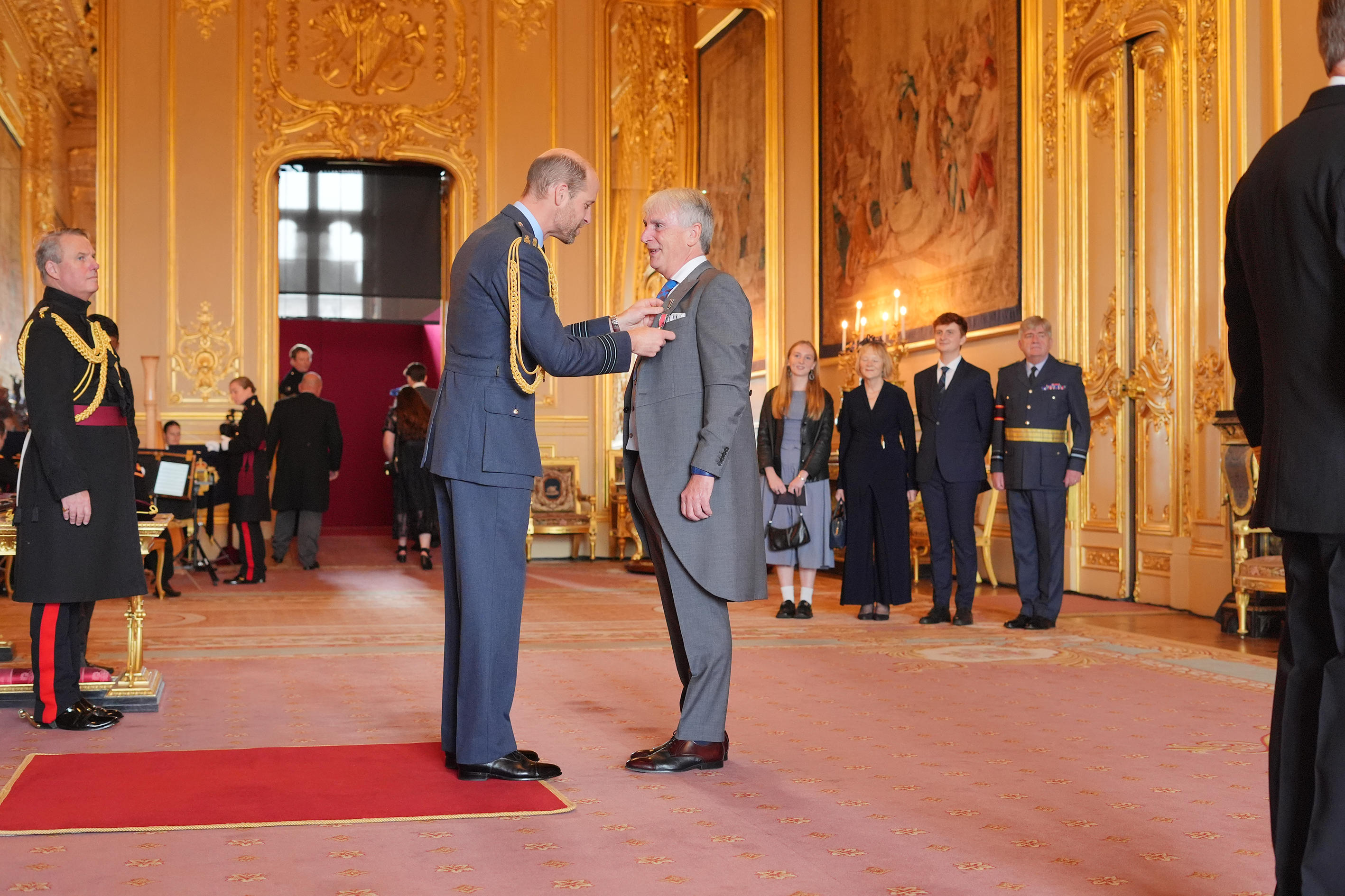 Prince William pinning an OBE on to Peter Dyer