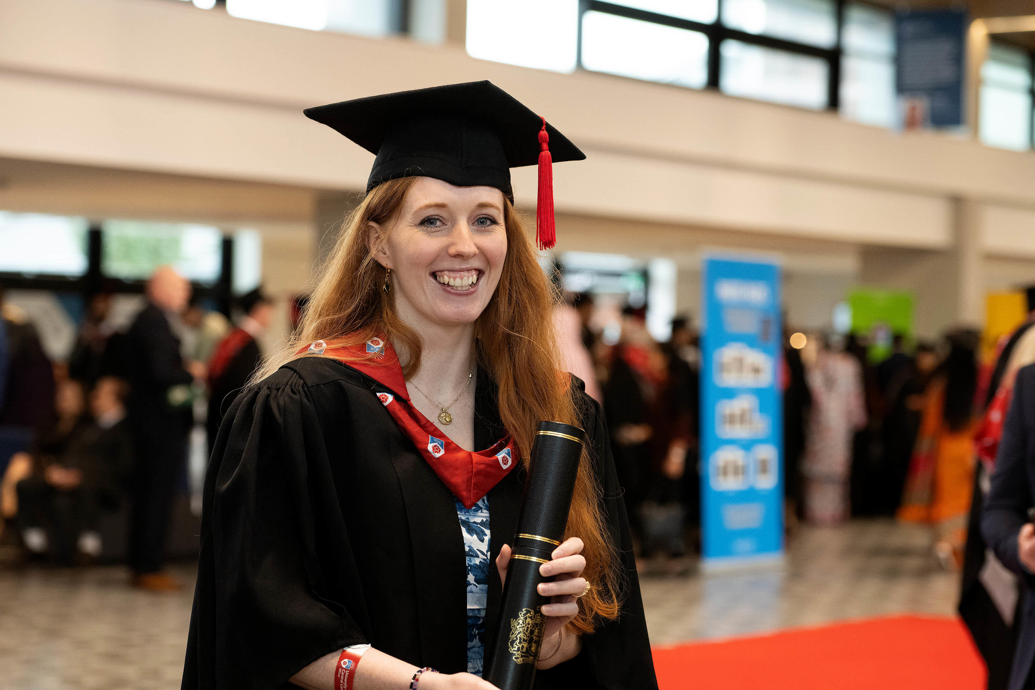 Stephanie Bowie-McIntosh dressed in her academic robes and holding a scroll