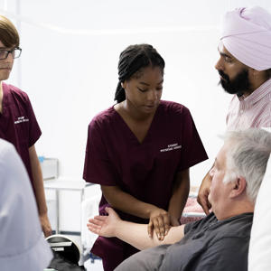 A patient in bed having his pulse taken