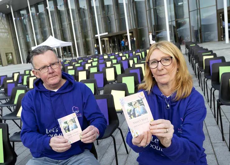 Paul and Sharon O'Gara, Mary's parents, holding information leaflets while sat on the chairs